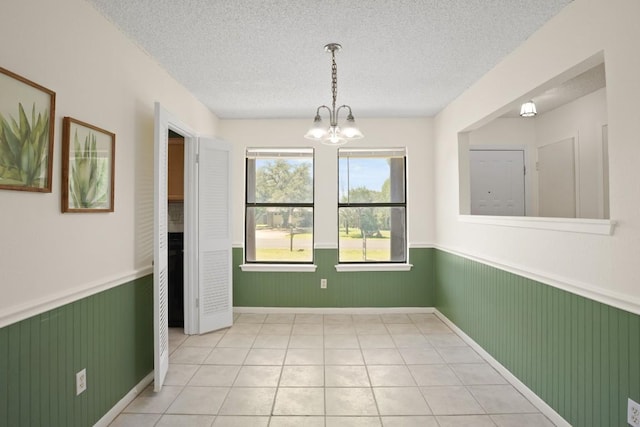 132 Spanish Oak Dr, Georgetown, TX 78628 - unfurnished dining area featuring a wainscoted wall, a textured ceiling, a chandelier, light tile patterned floors, and wood walls