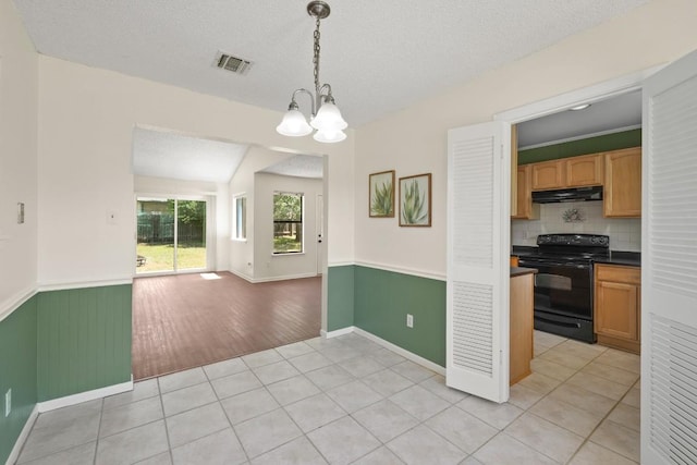 132 Spanish Oak Dr, Georgetown, TX 78628 - kitchen featuring black / electric stove, under cabinet range hood, open floor plan, a chandelier, and light tile patterned floors