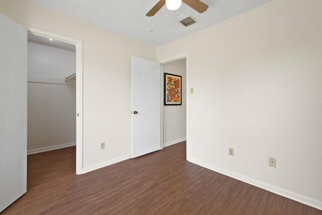 132 Spanish Oak Dr, Georgetown, TX 78628 - unfurnished bedroom with dark wood-style floors, a walk in closet, a closet, and ceiling fan