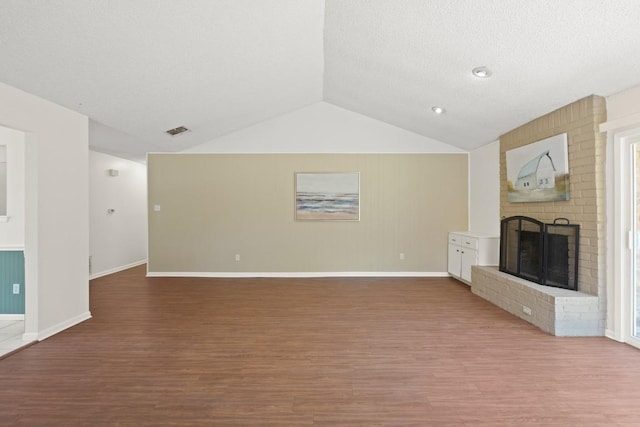 132 Spanish Oak Dr, Georgetown, TX 78628 - unfurnished living room with wood finished floors, vaulted ceiling, and a brick fireplace