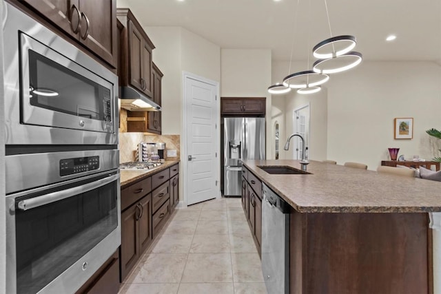9110 Bayshore Bnd Unit 30, Austin, TX 78726 - kitchen featuring stainless steel appliances, dark brown cabinetry, backsplash, an island with sink, and pendant lighting