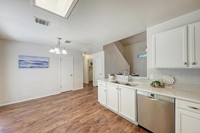 1803 Kwai Cv, Leander, TX 78641 - kitchen with stainless steel dishwasher, white cabinets, light wood-style floors, tasteful backsplash, and a textured ceiling