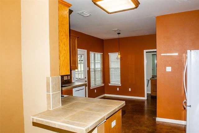 2003 White Dove Pass, Austin, TX 78734 - kitchen featuring white appliances, brown cabinetry, pendant lighting, finished concrete floors, and a peninsula