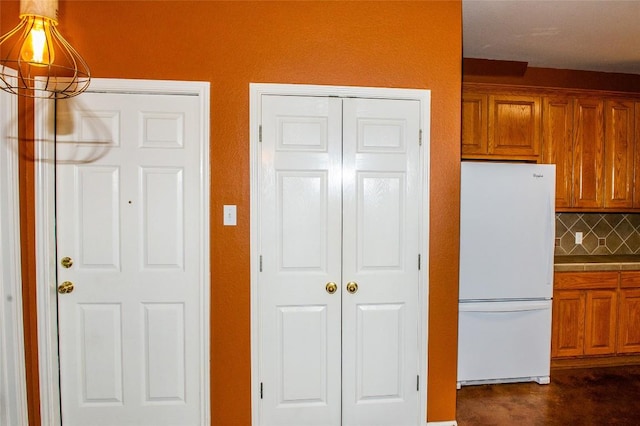 2003 White Dove Pass, Austin, TX 78734 - kitchen with freestanding refrigerator, tasteful backsplash, brown cabinetry, and tile counters