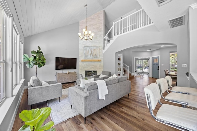 15001 Doria Dr, Austin, TX 78728 - living area featuring arched walkways, wood finished floors, a stone fireplace, high vaulted ceiling, and a chandelier