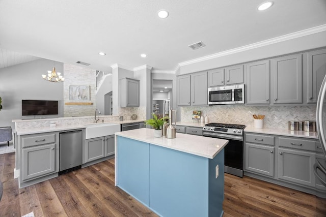 15001 Doria Dr, Austin, TX 78728 - kitchen with stainless steel appliances, gray cabinets, a center island, ornamental molding, and a chandelier