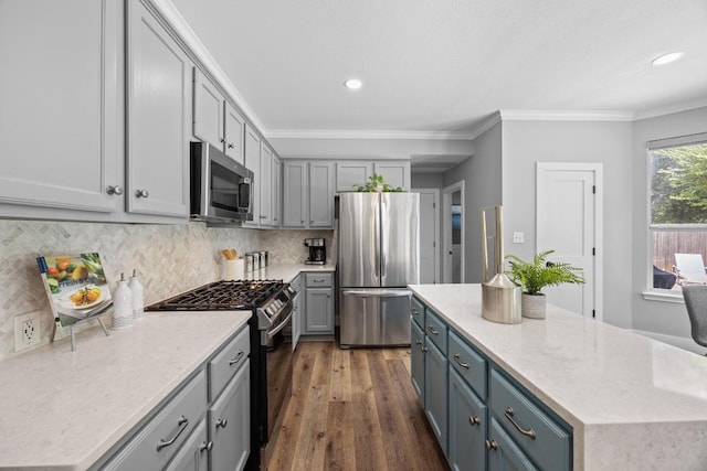 15001 Doria Dr, Austin, TX 78728 - kitchen with stainless steel appliances, dark wood finished floors, tasteful backsplash, ornamental molding, and gray cabinetry