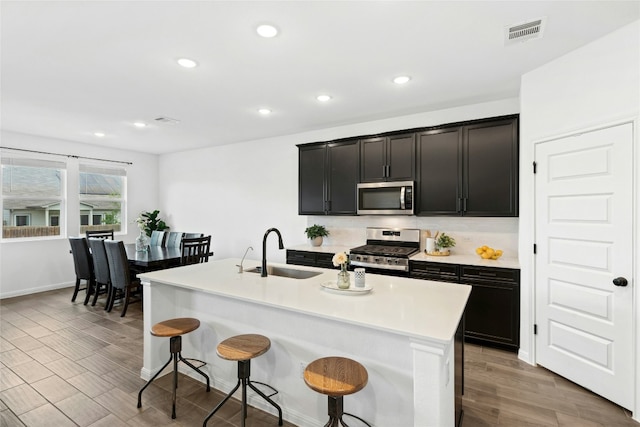 2616 Danbury Ln, Leander, TX 78641 - kitchen featuring appliances with stainless steel finishes, a breakfast bar area, light wood-style floors, light countertops, and recessed lighting