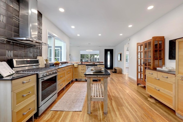 1708 Briar St, Austin, TX 78704 - kitchen with stainless steel gas stove, wall chimney exhaust hood, light wood-style flooring, recessed lighting, and a peninsula