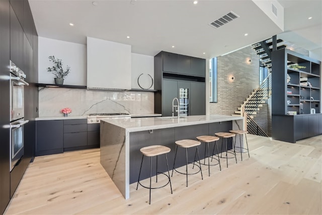 1315 W 9th St Unit B, Austin, TX 78703 - kitchen with modern cabinets, stainless steel appliances, light wood finished floors, a breakfast bar, and a large island