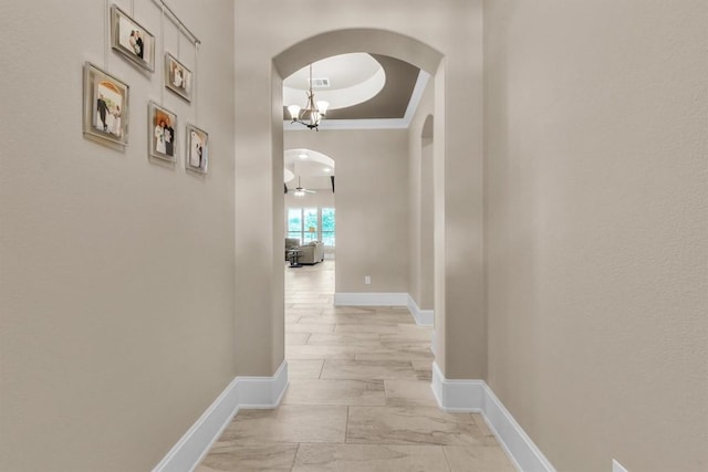 101 Dorado St, Georgetown, TX 78628 - corridor with arched walkways, a raised ceiling, a chandelier, ornamental molding, and light marble finish flooring