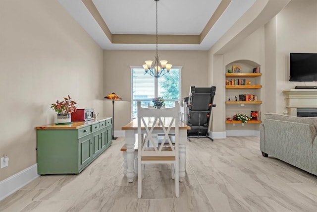 101 Dorado St, Georgetown, TX 78628 - dining space featuring a chandelier, built in features, light marble finish floors, a tray ceiling, and a fireplace