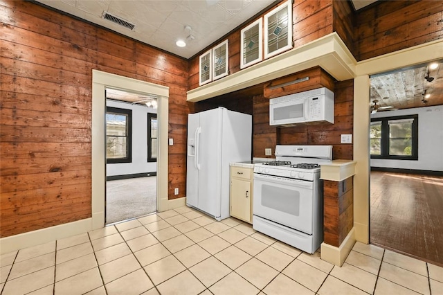 5112 Caswell Ave, Austin, TX 78751 - kitchen with white appliances, wooden walls, plenty of natural light, light countertops, and light tile patterned floors