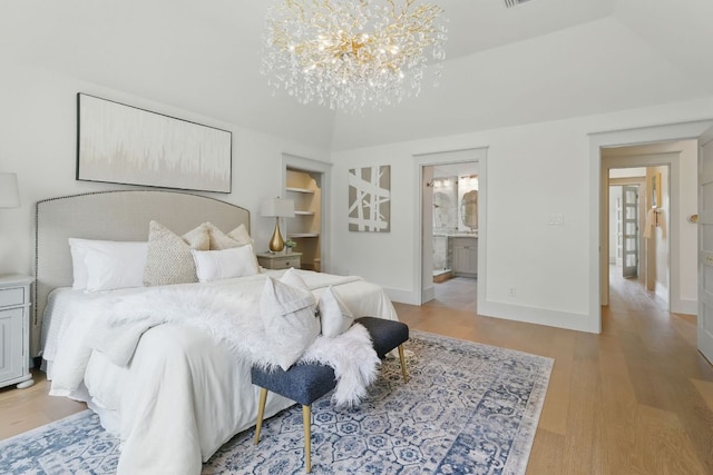 6905 Rudi Cv, Austin, TX 78759 - bedroom with a chandelier, light wood-type flooring, and ensuite bathroom
