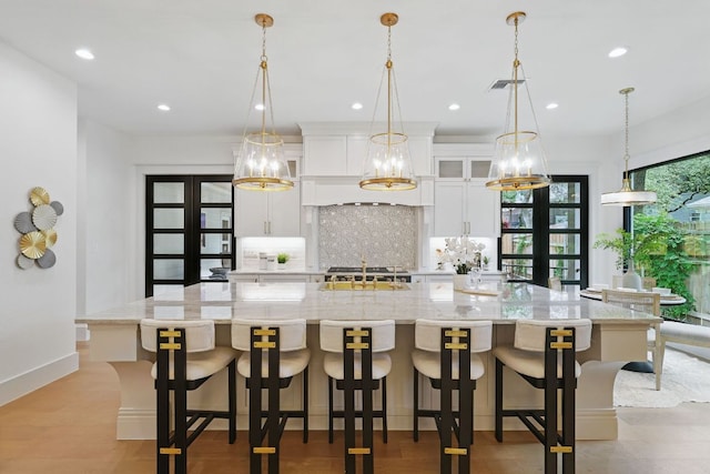 6905 Rudi Cv, Austin, TX 78759 - kitchen featuring tasteful backsplash, white cabinets, a spacious island, french doors, and recessed lighting