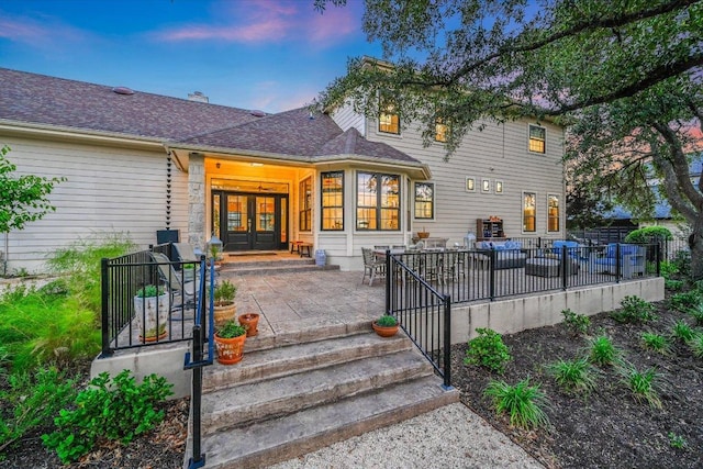 3342 Far View Dr, Austin, TX 78730 - exterior entry at dusk with french doors, a patio area, and a shingled roof