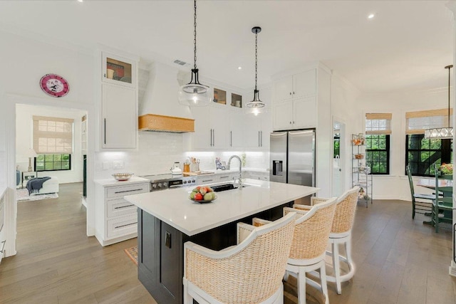 3342 Far View Dr, Austin, TX 78730 - kitchen with appliances with stainless steel finishes, white cabinets, custom range hood, light countertops, and an island with sink