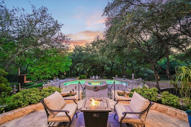 9105 Westminster Glen Ave, Austin, TX 78730 - patio terrace at dusk with a fire pit, a patio, view of scattered trees, and a pool with connected hot tub