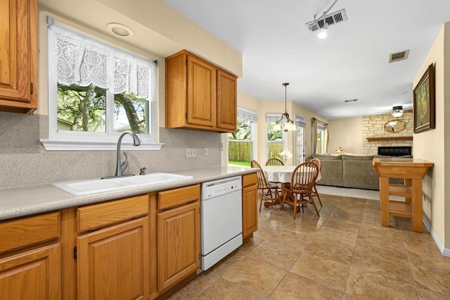 6712 Shiner St, Austin, TX 78729 - kitchen with white dishwasher, decorative backsplash, a brick fireplace, light countertops, and brown cabinets