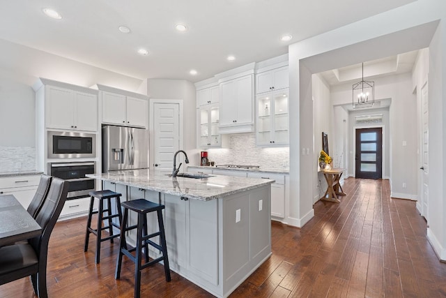 164 Mary Cornelia Cv, Buda, TX 78610 - kitchen with stainless steel appliances, backsplash, white cabinetry, a kitchen breakfast bar, and light stone countertops