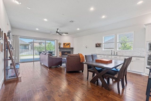 164 Mary Cornelia Cv, Buda, TX 78610 - dining space featuring dark wood-style flooring, a warm lit fireplace, ceiling fan, and recessed lighting