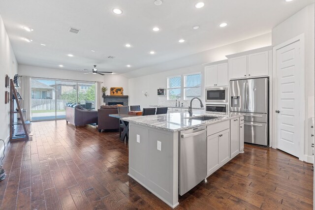 164 Mary Cornelia Cv, Buda, TX 78610 - kitchen with appliances with stainless steel finishes, a fireplace, recessed lighting, dark wood-type flooring, and light stone counters