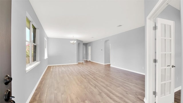 1086 Sussex Way, Round Rock, TX 78665 - unfurnished room featuring light wood-type flooring, a chandelier, and arched walkways