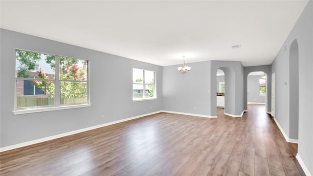 1086 Sussex Way, Round Rock, TX 78665 - spare room featuring arched walkways, a chandelier, and wood finished floors