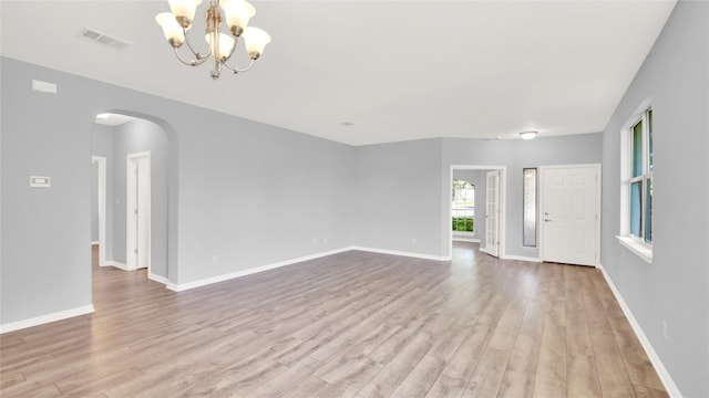 1086 Sussex Way, Round Rock, TX 78665 - unfurnished living room with wood finished floors, arched walkways, and a chandelier