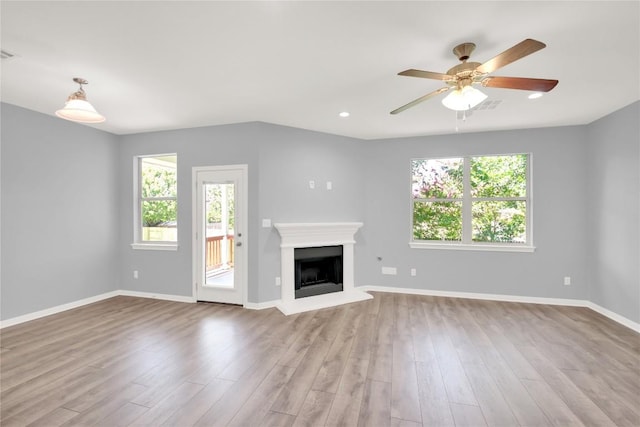 1086 Sussex Way, Round Rock, TX 78665 - unfurnished living room featuring plenty of natural light, a fireplace with raised hearth, wood finished floors, and recessed lighting
