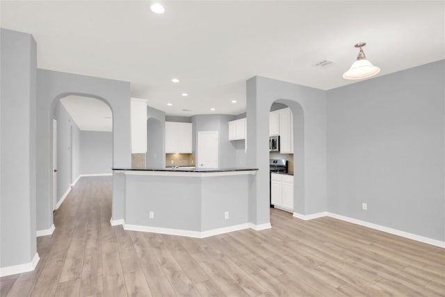 1086 Sussex Way, Round Rock, TX 78665 - kitchen with appliances with stainless steel finishes, light wood finished floors, arched walkways, dark countertops, and recessed lighting