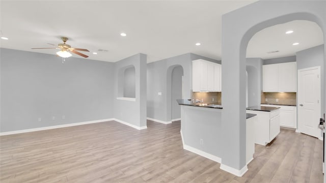 1086 Sussex Way, Round Rock, TX 78665 - kitchen featuring arched walkways, ceiling fan, dark countertops, white cabinetry, and light wood finished floors
