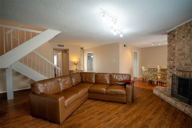 8403 Ardash Ln, Austin, TX 78759 - living room featuring stairs, wood finished floors, track lighting, a textured ceiling, and a fireplace