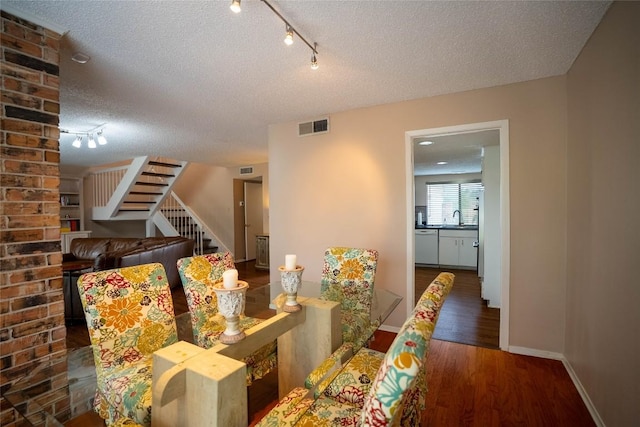8403 Ardash Ln, Austin, TX 78759 - dining room featuring track lighting, a textured ceiling, wood finished floors, and stairs