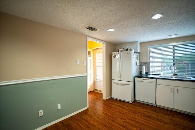 8403 Ardash Ln, Austin, TX 78759 - kitchen with white appliances, dark wood finished floors, a textured ceiling, dark countertops, and white cabinets
