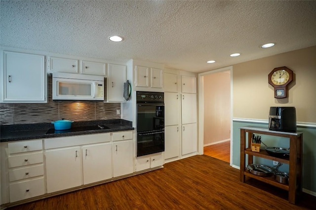 8403 Ardash Ln, Austin, TX 78759 - kitchen featuring black appliances, a textured ceiling, dark wood finished floors, white cabinetry, and dark countertops
