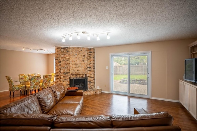 8403 Ardash Ln, Austin, TX 78759 - living area featuring wood finished floors, a fireplace, a textured ceiling, and rail lighting