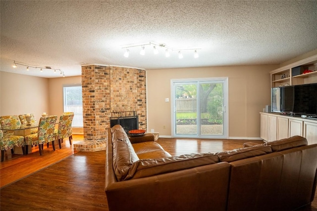 8403 Ardash Ln, Austin, TX 78759 - living room featuring dark wood finished floors, a textured ceiling, plenty of natural light, track lighting, and a brick fireplace