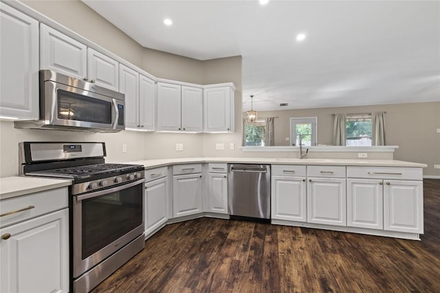 3203 Saint Genevieve Dr, Leander, TX 78641 - kitchen with appliances with stainless steel finishes, a peninsula, light countertops, dark wood finished floors, and white cabinets