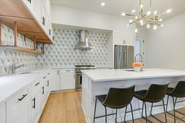 902 W Live Oak St, Austin, TX 78704 - kitchen with appliances with stainless steel finishes, wall chimney range hood, a breakfast bar, and light wood finished floors
