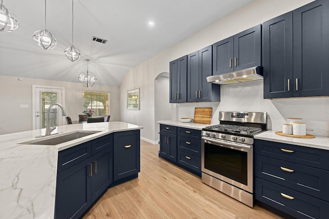 101 Desert Highlands Trl, Round Rock, TX 78665 - kitchen featuring stainless steel gas range oven, under cabinet range hood, arched walkways, light wood-style floors, and light stone countertops
