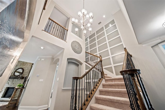 108 Kildrummy Ln, Lakeway, TX 78738 - stairs with a chandelier, a towering ceiling, built in features, a stone fireplace, and crown molding