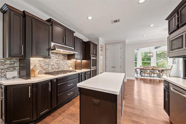 108 Kildrummy Ln, Lakeway, TX 78738 - kitchen featuring under cabinet range hood, stainless steel appliances, ornamental molding, a center island, and light countertops