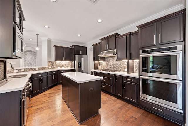 108 Kildrummy Ln, Lakeway, TX 78738 - kitchen featuring appliances with stainless steel finishes, ornamental molding, a center island, light countertops, and tasteful backsplash