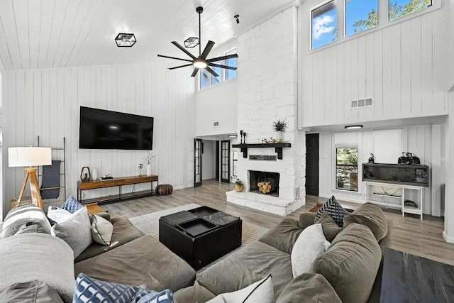 11803 Jess Dr, Austin, TX 78737 - living room featuring high vaulted ceiling, a ceiling fan, wood walls, wood finished floors, and a stone fireplace