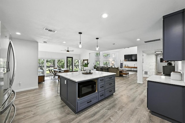 11803 Jess Dr, Austin, TX 78737 - kitchen with black microwave, freestanding refrigerator, open floor plan, light countertops, and ceiling fan
