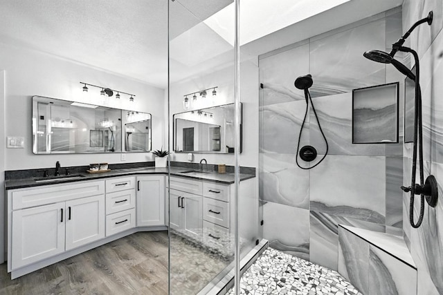 11803 Jess Dr, Austin, TX 78737 - bathroom with a stall shower, wood finished floors, double vanity, and a textured ceiling