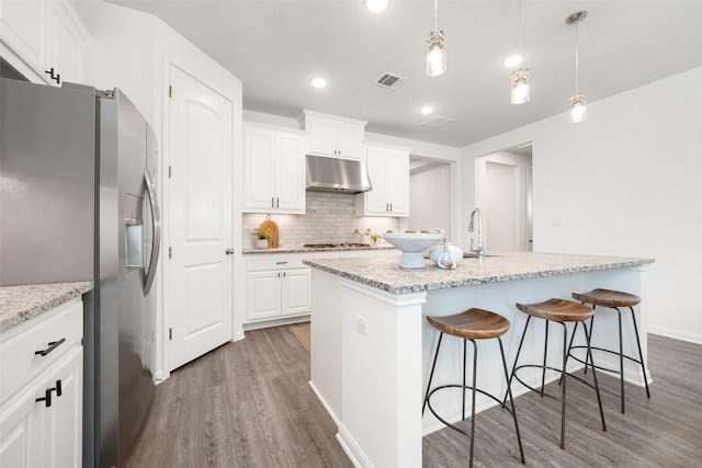 2541 Reunion Blvd, Austin, TX 78737 - kitchen with appliances with stainless steel finishes, under cabinet range hood, wood finished floors, backsplash, and white cabinetry