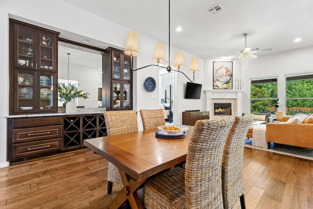 2977 Diego Dr, Round Rock, TX 78665 - dining room featuring wood-type flooring, a ceiling fan, a lit fireplace, and recessed lighting