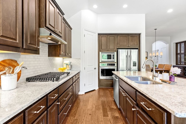 2977 Diego Dr, Round Rock, TX 78665 - kitchen with stainless steel appliances, under cabinet range hood, dark wood finished floors, a chandelier, and light stone counters